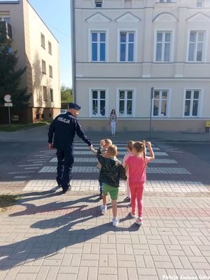 Policjant przeprowadza przedszkolaków przez pasy.