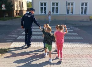 Policjant przeprowadza przedszkolaków przez pasy.