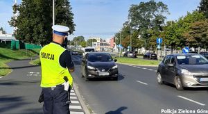 Policjant ruchu drogowego mierzący prędkość nadjeżdżających samochodów.