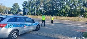 Dwójka policjantów z ruchu drogowego mierzą prędkość nadjeżdżających samochodów.