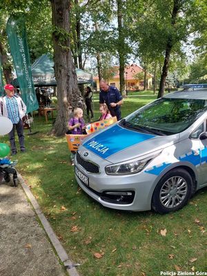 Policjant poprzez zabawę uczy dzieci bezpieczeństwa obok radiowozu