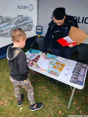 Chłopczyk stojący z policjantką przy policyjnym stoisku