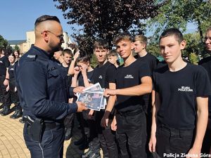 Policjant rozdaje ulotki zostań zielonogórskim policjantem