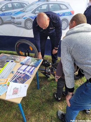 Policjant znakuje rower chętnej osobie i z nią rozmawia