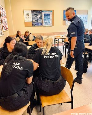 Policjant sprawdza jak idzie uczniom klasy policyjnej praca w grupach