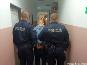 Dwóch policjantów prowadzi zatrzymanego mężczyznę