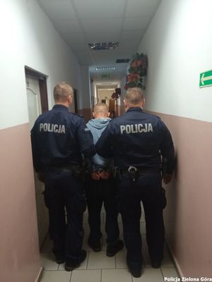 Dwóch policjantów prowadzi zatrzymanego mężczyznę