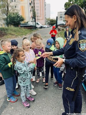 Funkcjonariuszka Straży Miejskiej rozdaje dzieciom upominki