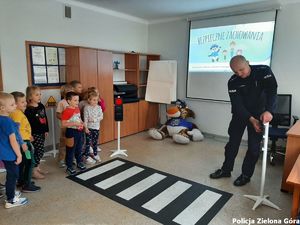 Policjant uczy dzieci bezpiecznego przechodzenia przez przejścia dla pieszych