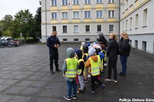 Policjant oprowadza dzieci po terenie komendy