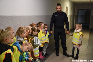 Policjant oprowadza dzieci po terenie komendy