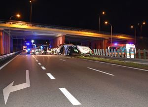 Straż pożarna i ambulans zabezpieczają miejsce wypadku samochodu ciężarowego pod wiaduktem na drodze ekspresowej