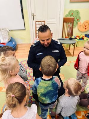 Policjant rozmawia z dziećmi i pokazuje im kajdanki