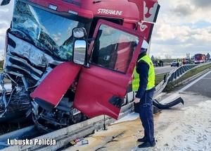 Policjant Ruchu Drogowego zagląda do środka rozwalonej kabiny pojazdu ciężarowego