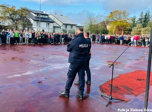 Dwóch policjantów rozmawia z młodzieżą na boisku Zespołu Szkół Technicznych w Zielonej Górze