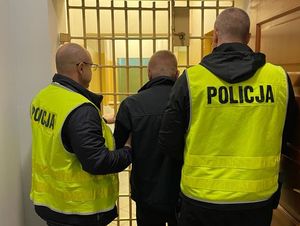 Policjanci prowadzą zatrzymanego kierowcę