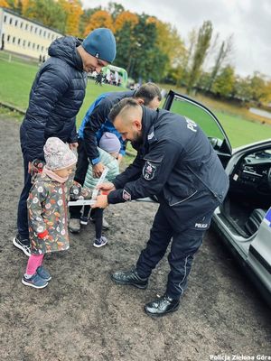 Policjant przekazuje upominki dzieciom