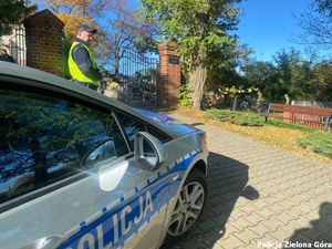 Policjant pilnuje porządku przy wejściu na cmentarz