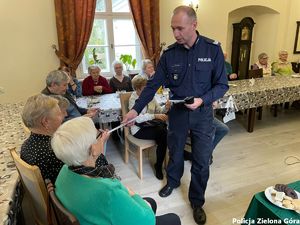 Policjant rozdaje ulotki seniorom