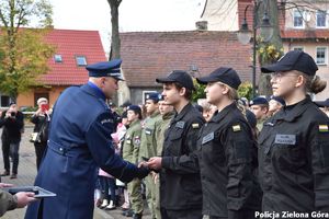 Zastępca komendanta komisarz Krzysztof Marciniak wręcza uczniowi symboliczne pagony kadetów klasy mundurowej i gratuluje