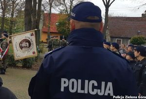 Policjant widziany od tyłu z uczniami liceum i sztandarem szkoły w Czerwieńsku