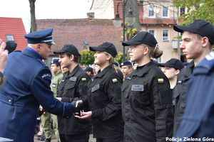 Zastępca komendanta komisarz Krzysztof Marciniak wręcza uczennicy symboliczne pagony kadetów klasy mundurowej i gratuluje