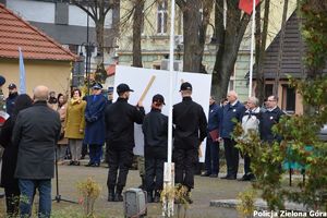 Uczniowie trzymają flagę przy pomniku Pamięci