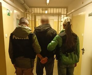 Policjanci prowadzą zatrzymanego mężczyznę