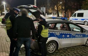 Policjanci Ruchu Drogowego rozmawiają z mężczyzną przy radiowozie