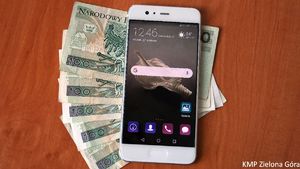 Biały telefon położony na banknotach stuzłotowych