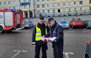 Policjanci stoją przed komendą Miejską Policji i sprawdzają czy wszyscy się ewakuowali