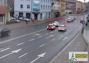 Kadr z nagrania gdzie biała taksówka skręca w niedozwolonym miejscu przekraczając linię podwójną ciągłą