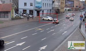 Kadr z nagrania gdzie biała taksówka skręca w niedozwolonym miejscu przekraczając linię podwójną ciągłą