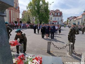 Uroczyste składanie wieńca przed pomnikiem przez żołnierzy,w tle delegacja policji w umundurowaniu galowym .