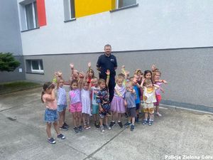 Dzieci z rękoma do góry pozują z policjantem.