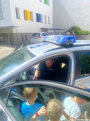 Policjant pokazuje dzieciom wnętrze radiowozu.