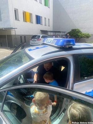 Policjant pokazuje dzieciom wnętrze radiowozu.