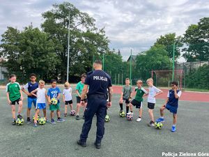 Policjant rozmawia z dziećmi na boisku.