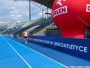 Policjantka pozuje przy napisie &quot;100. Mistrzostwa Polski w lekkoatletyce.&quot;