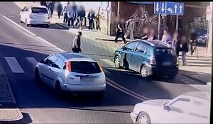 zdjęcie przedstawia pieszego na przejściu. Na lewym pasie zatrzymał się kierowca srebrnego pojazdu aby przepuścić pieszego. Kierujący zielonym autem jadący prawym pasem wjechał na przejście pomimo, że znajdował się już na nim pieszy