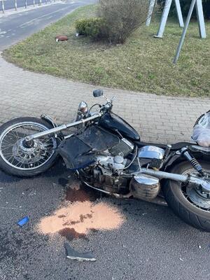 Na zdjeciu widać leżący na jezdni uszkodzony motocykl po wypadku drogowym.