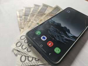 zdjęcie przedstawia telefon komórkowy leżący na banknotach 200 złotowych